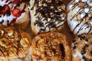 Assorted gourmet donuts topped with fruit, chocolate drizzle, marshmallows, and caramel at the Doughbox Bakery