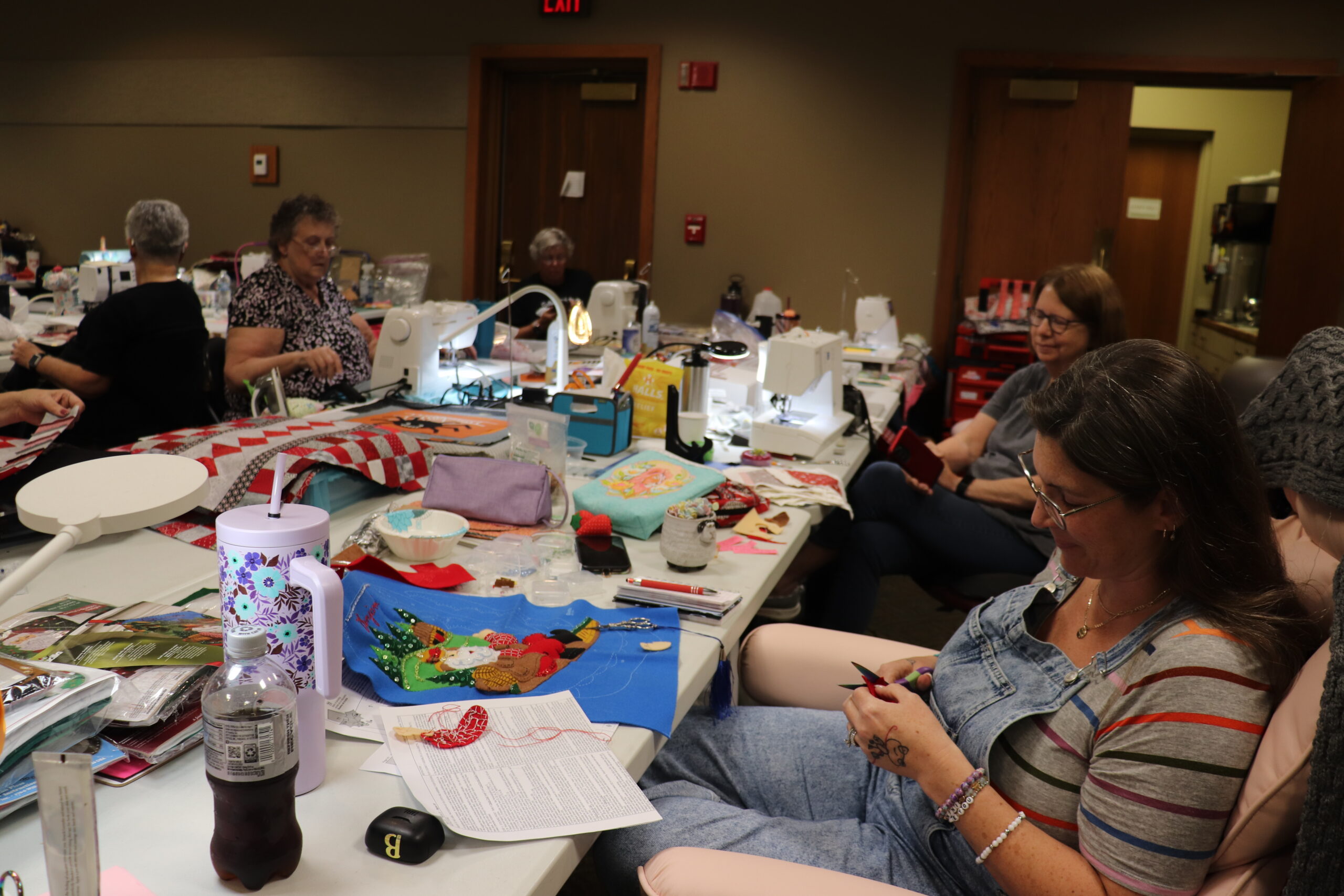 Women hand-stitching and quilting at long tables during a maker retreat at Sauder Village