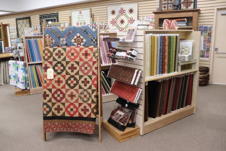 Quilts and fabric bolts displayed in a quilt shop, showcasing patterns and kits available at Sauder Village