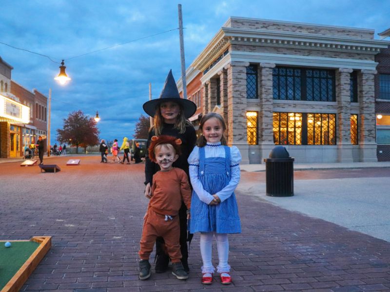 Children in Halloween costumes on the 1920s Main Street at dusk