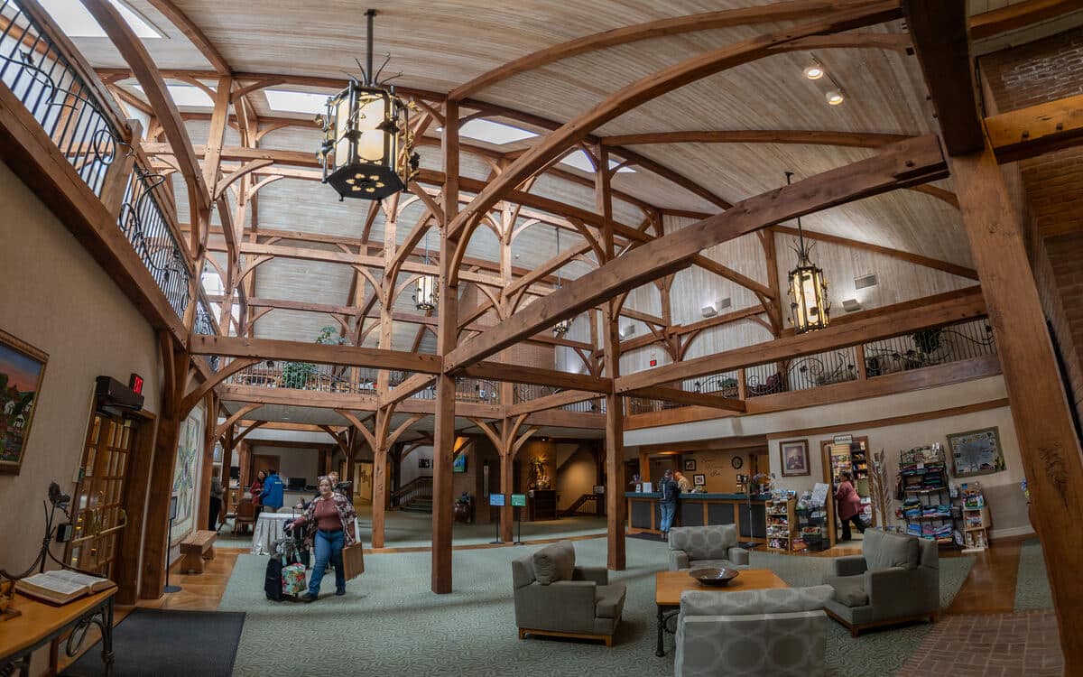 Timber-frame lobby of the Sauder Heritage Inn with a guest arriving with luggage