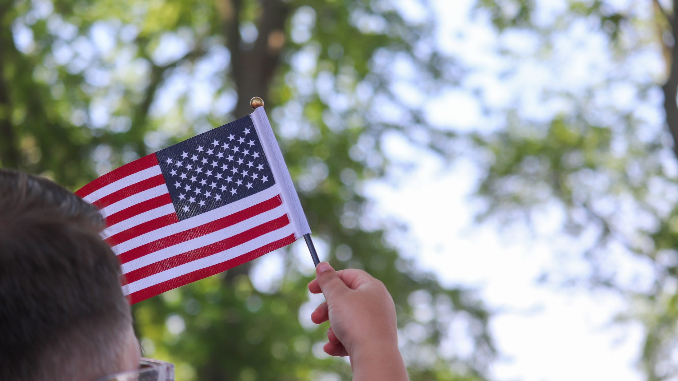 Guest waving a small American flag at Sauder Village's Fourth of July celebration